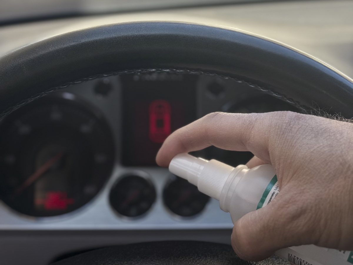 Spraying interior cleaner onto a steering wheel and dash